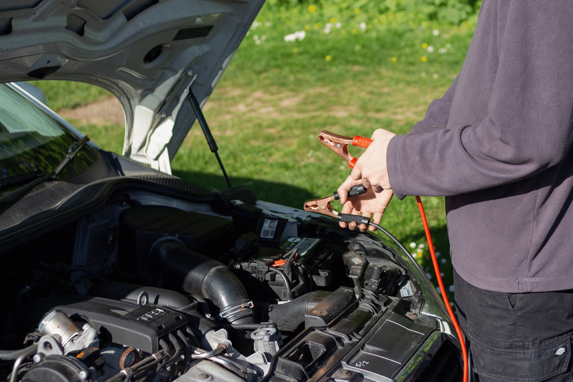 A person jumpstarts a car.